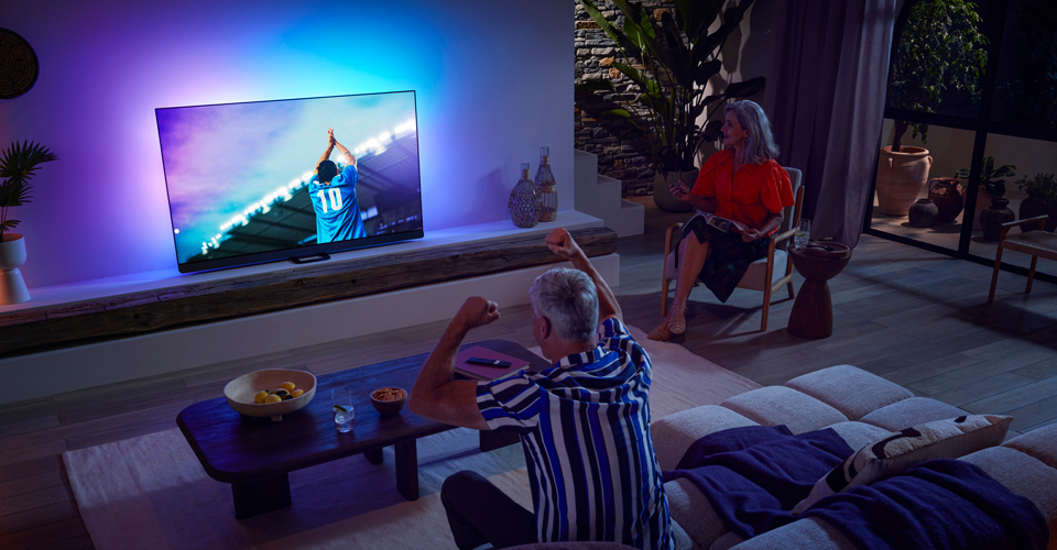 Familj tittar p&aring; match med OLED-TV