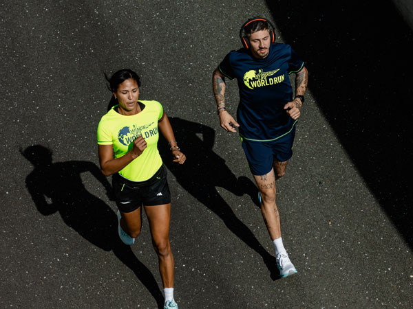 Tv&aring; deltagare som springer f&ouml;r att h&aring;lla sig f&ouml;re m&aring;llinjebilen.