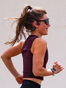Kvinna som springer med bone conduction-h&ouml;rlurar